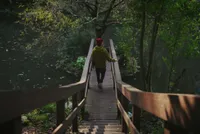 Person crossing a recycled plastic walkway, floema model, installed in a natural park.