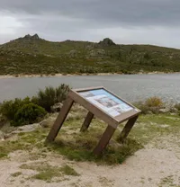 Mesa interpretativa ICNF em plástico reciclado Floema num vale da Serra da estrela com lagoa e montanhas no fundo.