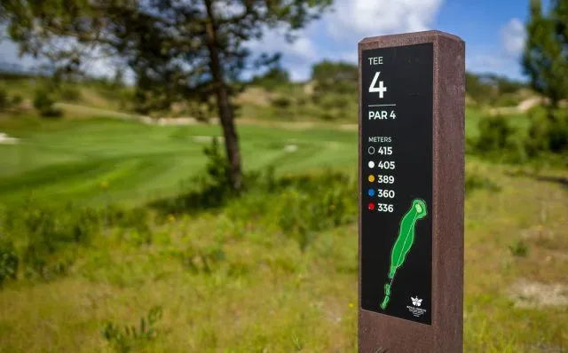 Detalhe de tee totem Royal da Floema com funcado desfocado de campo de golfe. Sinalética com estrutura em plástico reciclado castanho e HPL+. 