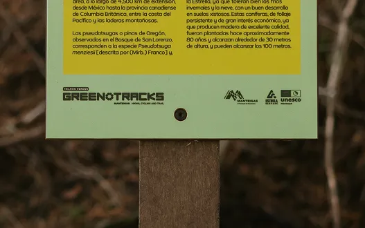 Detalhe de placa informativa para percursos pedestres modelo Floema em HPL Print. Instalada em poste de plástico reciclado castanho em área natural.