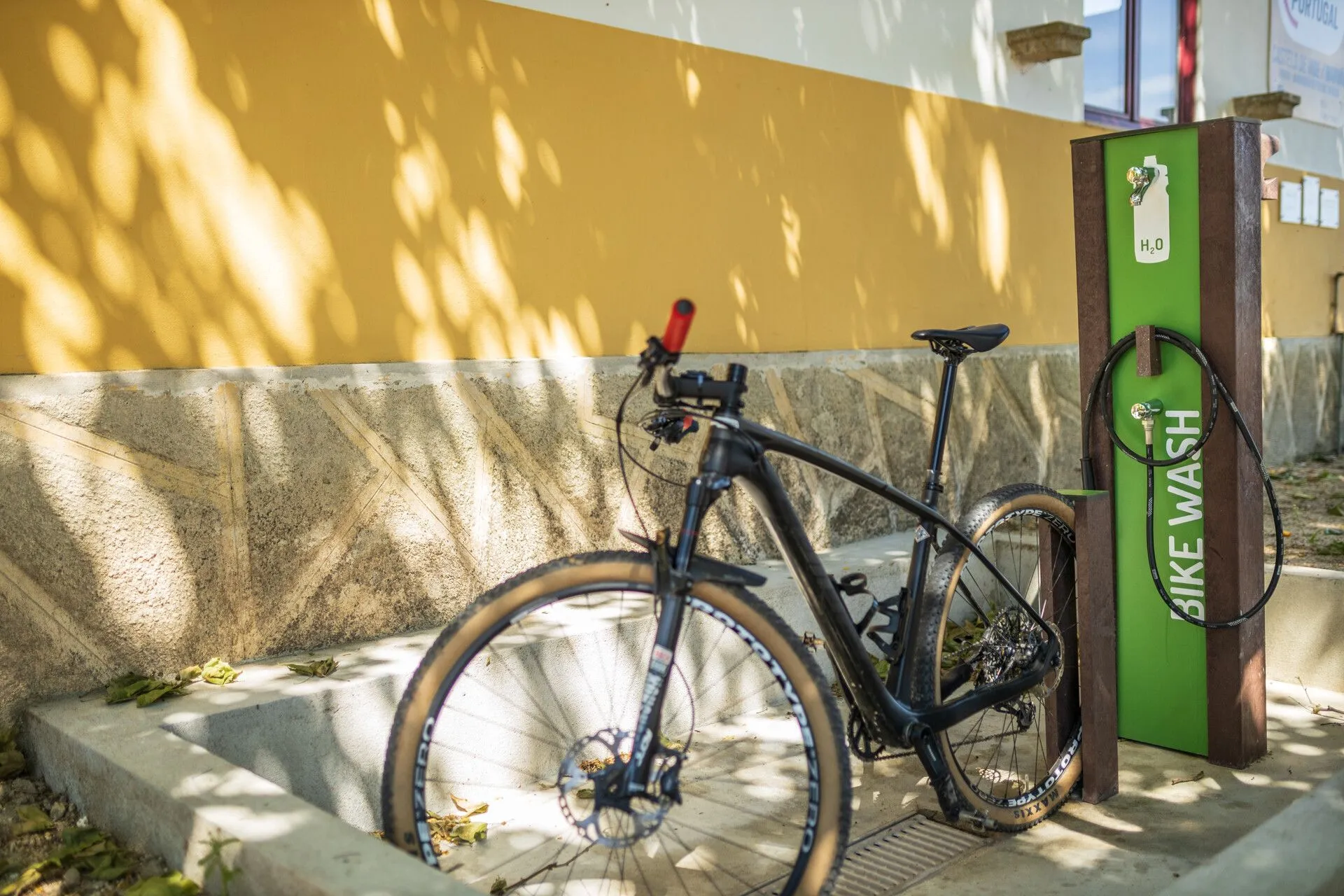 Bike station low tech modelo Floema com estrutura em plástico reciclado castanho e suporte para estacionamento de bicicleta com bicicleta de BTT.