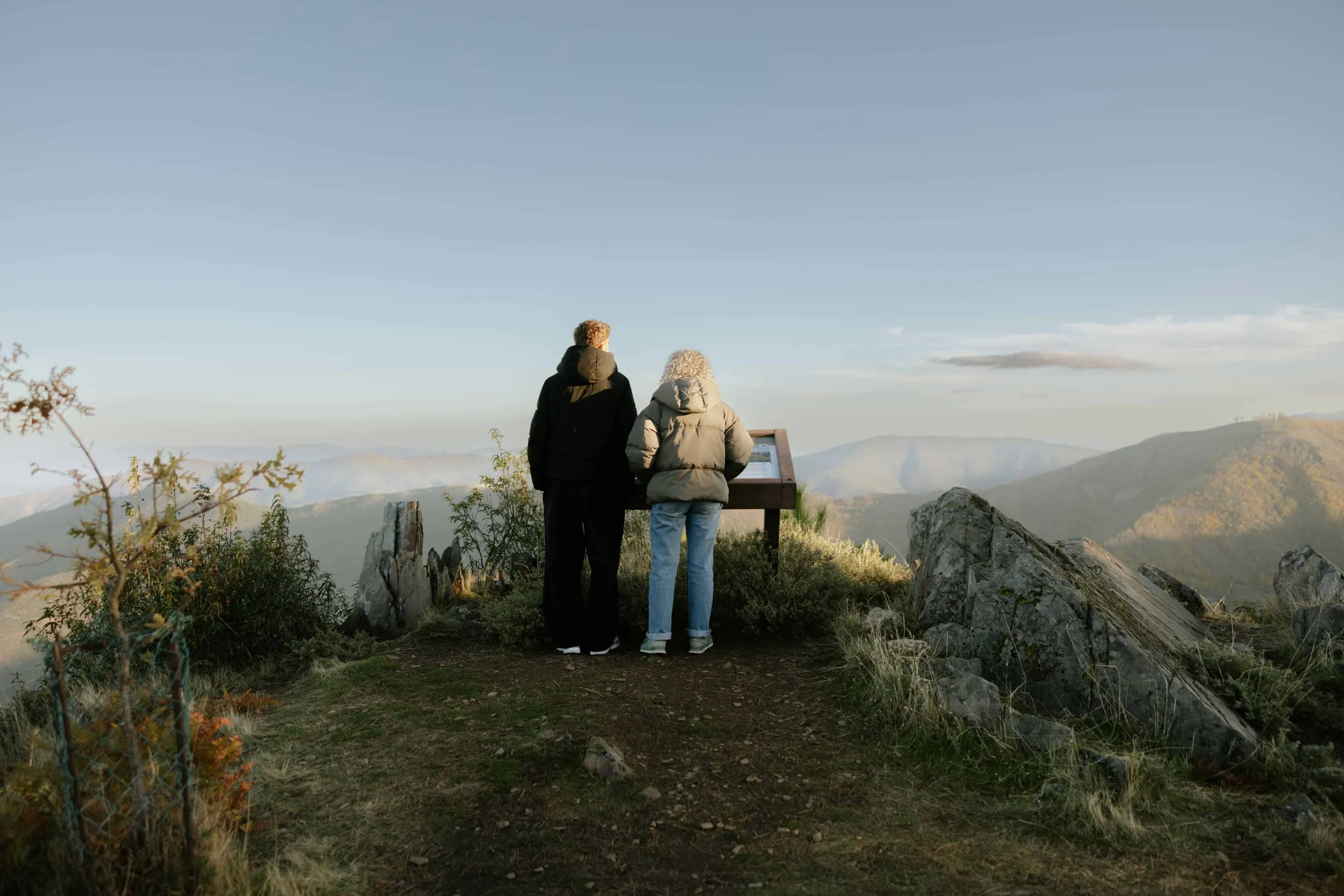 Duas pessoas a ler conteúdos de mesa interpretativa ICNF em plástico reciclado na Serra da Estrela.