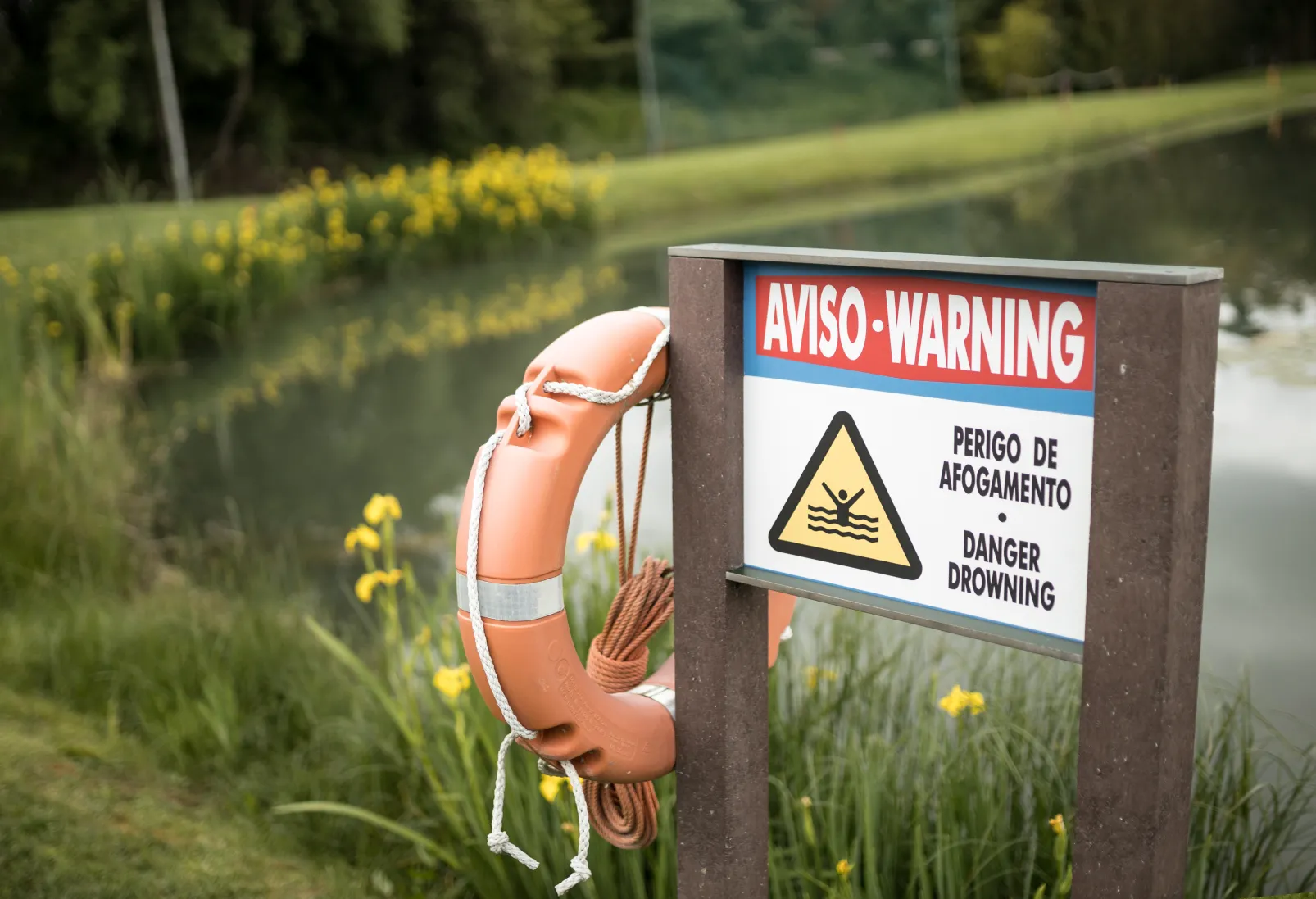 Detalhe de painel informativo de campo de golfe com estrutura em plástico reciclado castanho e com suporte e bóia salva-vidas.