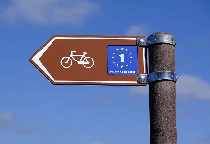 Placa direcional de rotas cicláveis em HPL+ com personalização para a rota da EuroVelo. Inclui poste em plástico reciclado castanho e sistema de fixação com abraçadeiras em aço inoxidável.