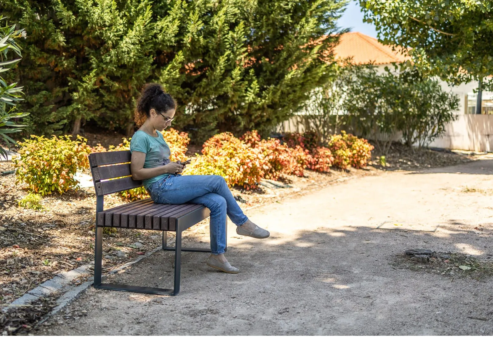 Pessoa sentada no banco Frame da Floema com encosto em plástico reciclado no meio do parque.