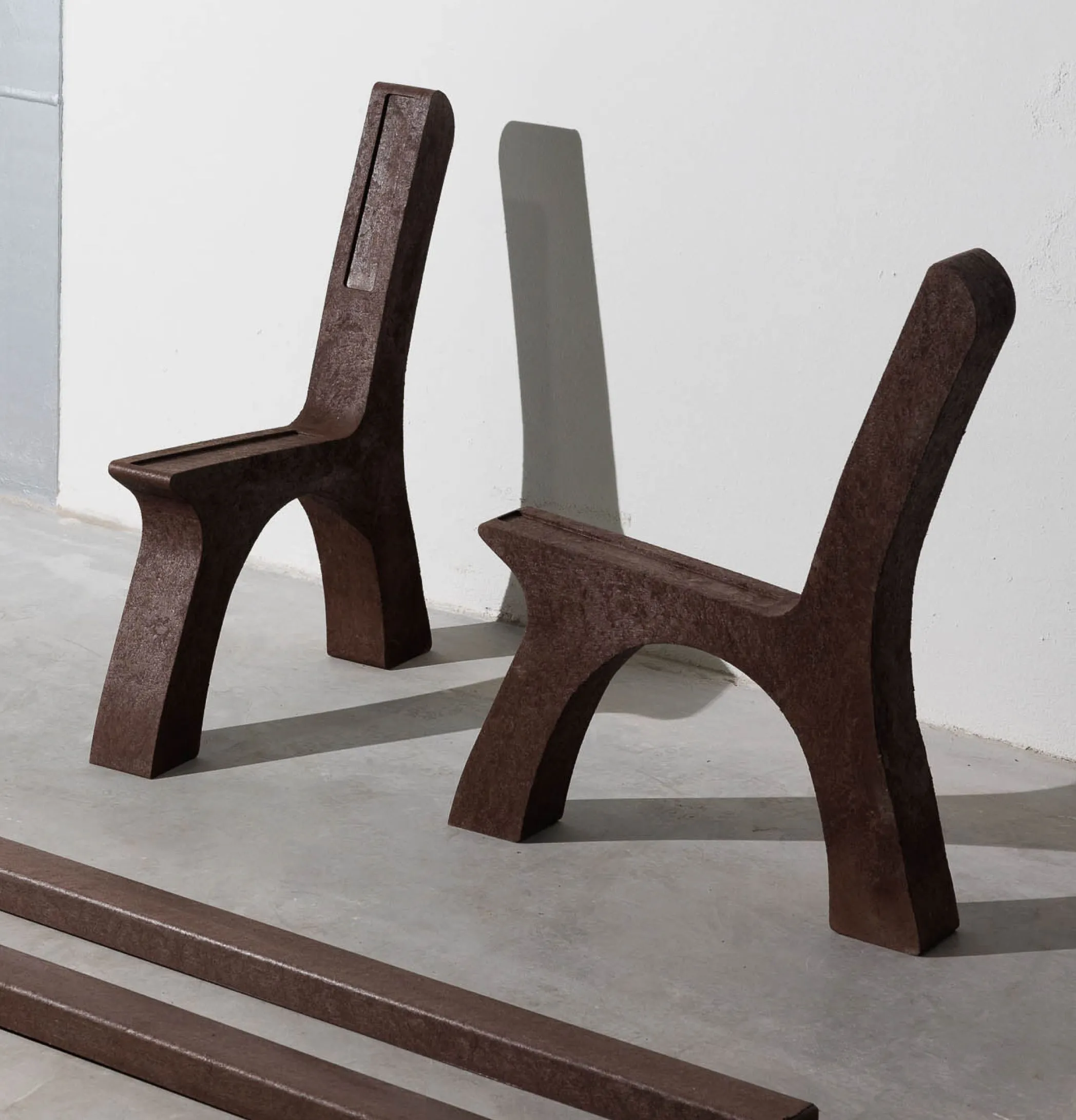 Peças de banco e perfis em plástico reciclado castanho Floema em chão de fábrica.