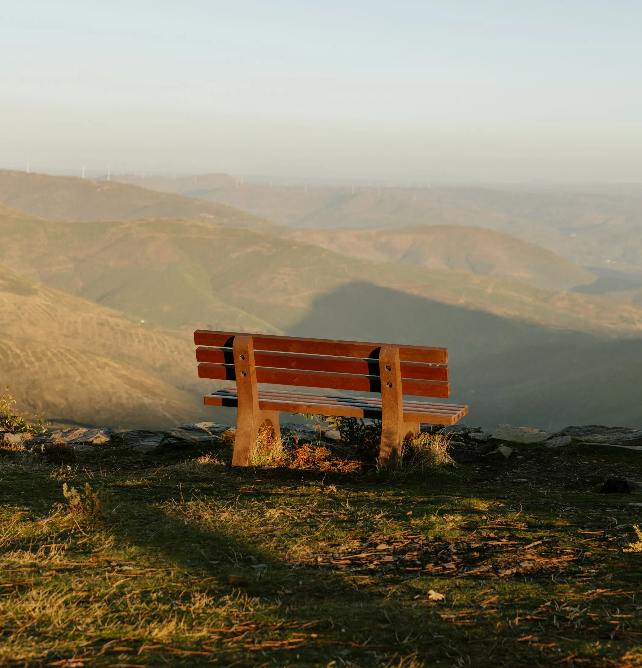 Banco em plástico reciclado castanho Floema em área natural. Vista das montanhas de fundo.