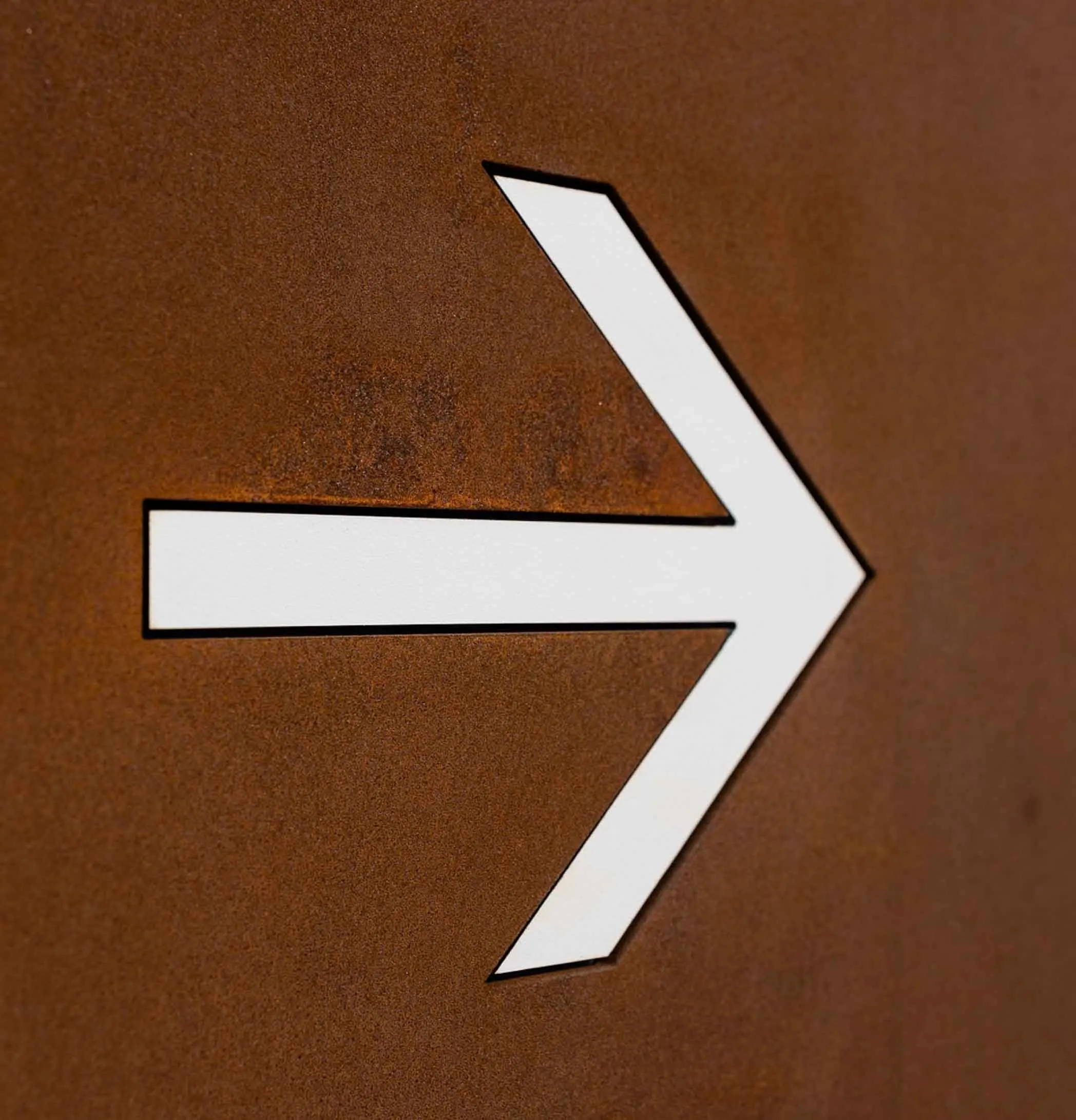 Detalhe de seta vazada com negativo em HPL de totem direcional personalizado em aço corten para rota urbana.