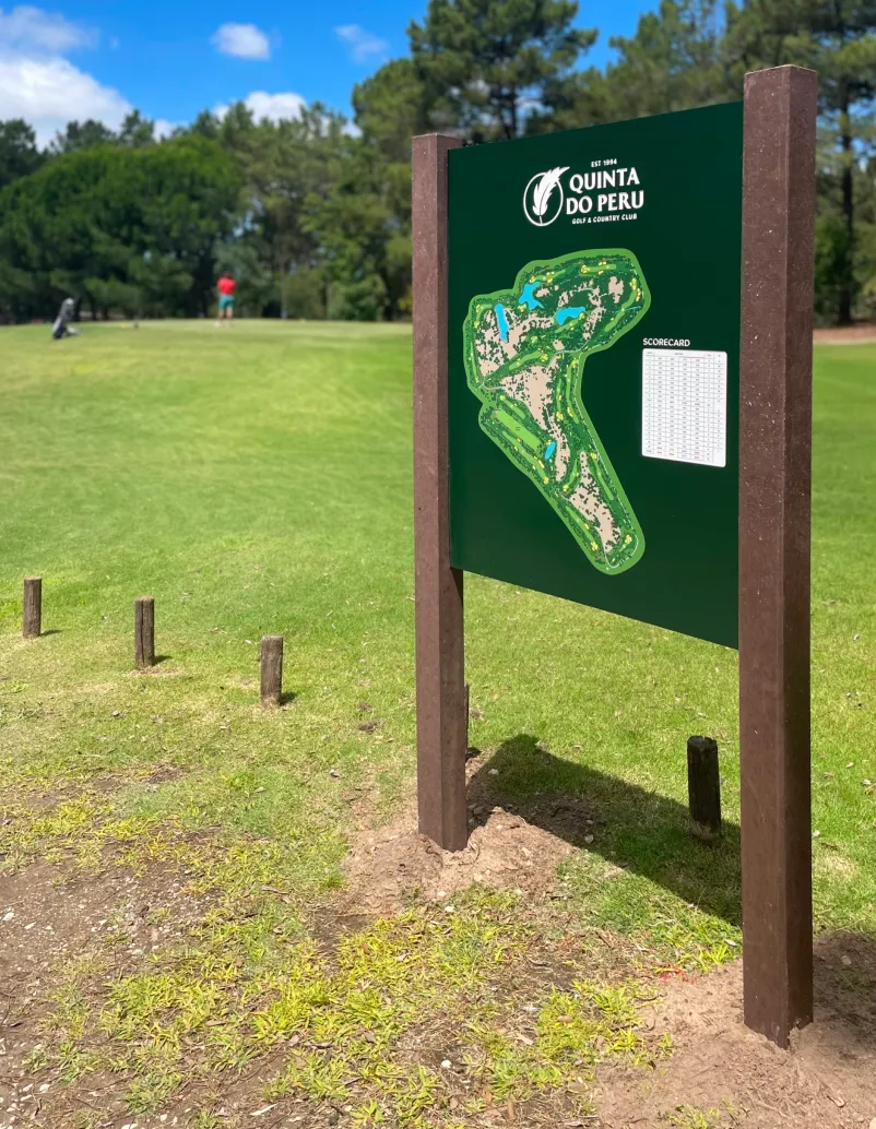 Mapa de campo para Clubhouse com estrutura em plástico reciclado e painel em HPL e vinil polimérico. Jogador na área de tee a jogar golfe.