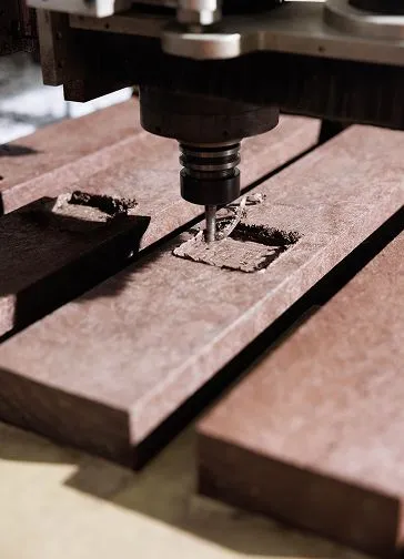 Máquina de fresagem CNC a esculpir um encaixe retangular em tábuas de madeira escura