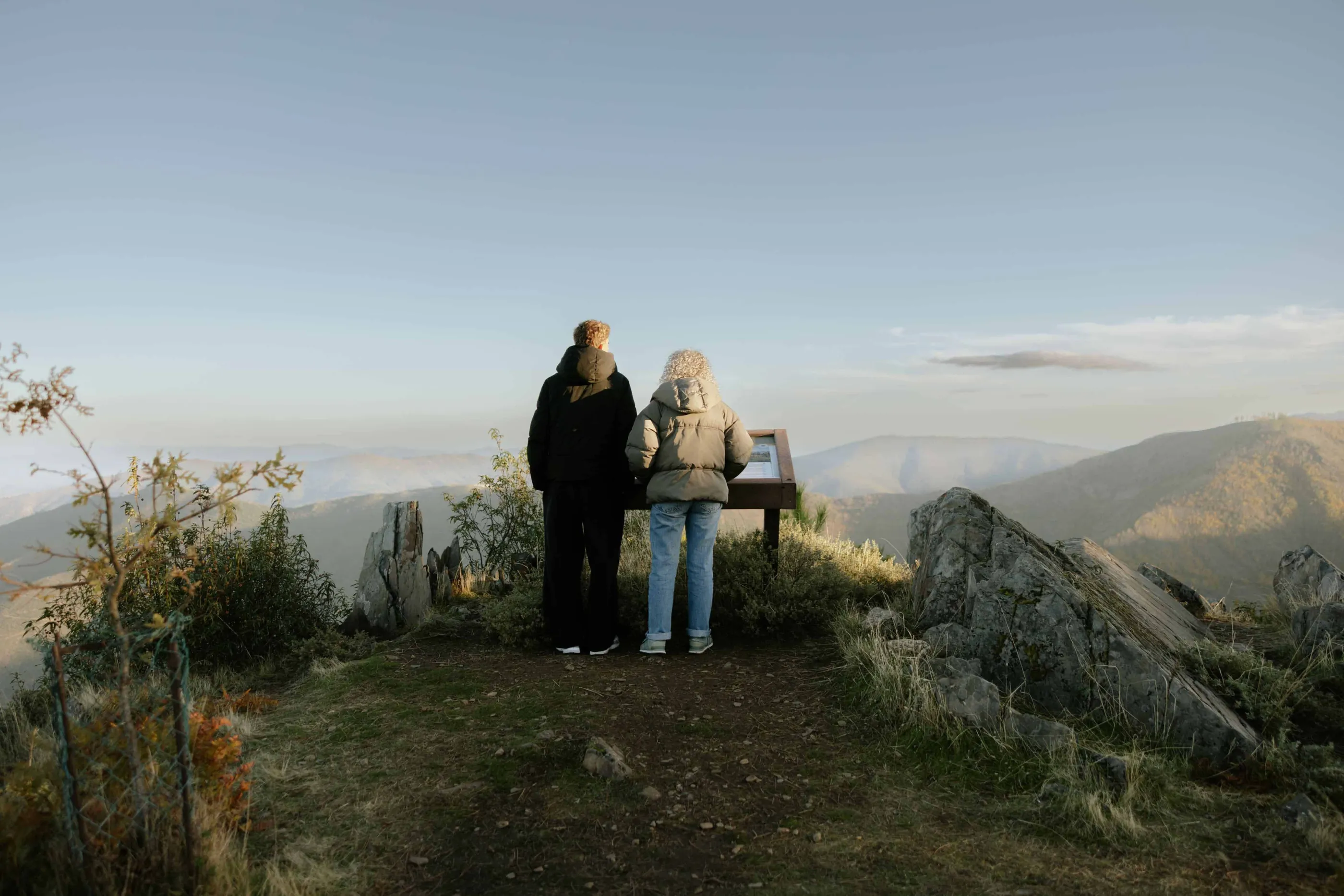 Duas pessoas a ler conteúdos de mesa interpretativa ICNF em plástico reciclado na Serra da Estrela.
