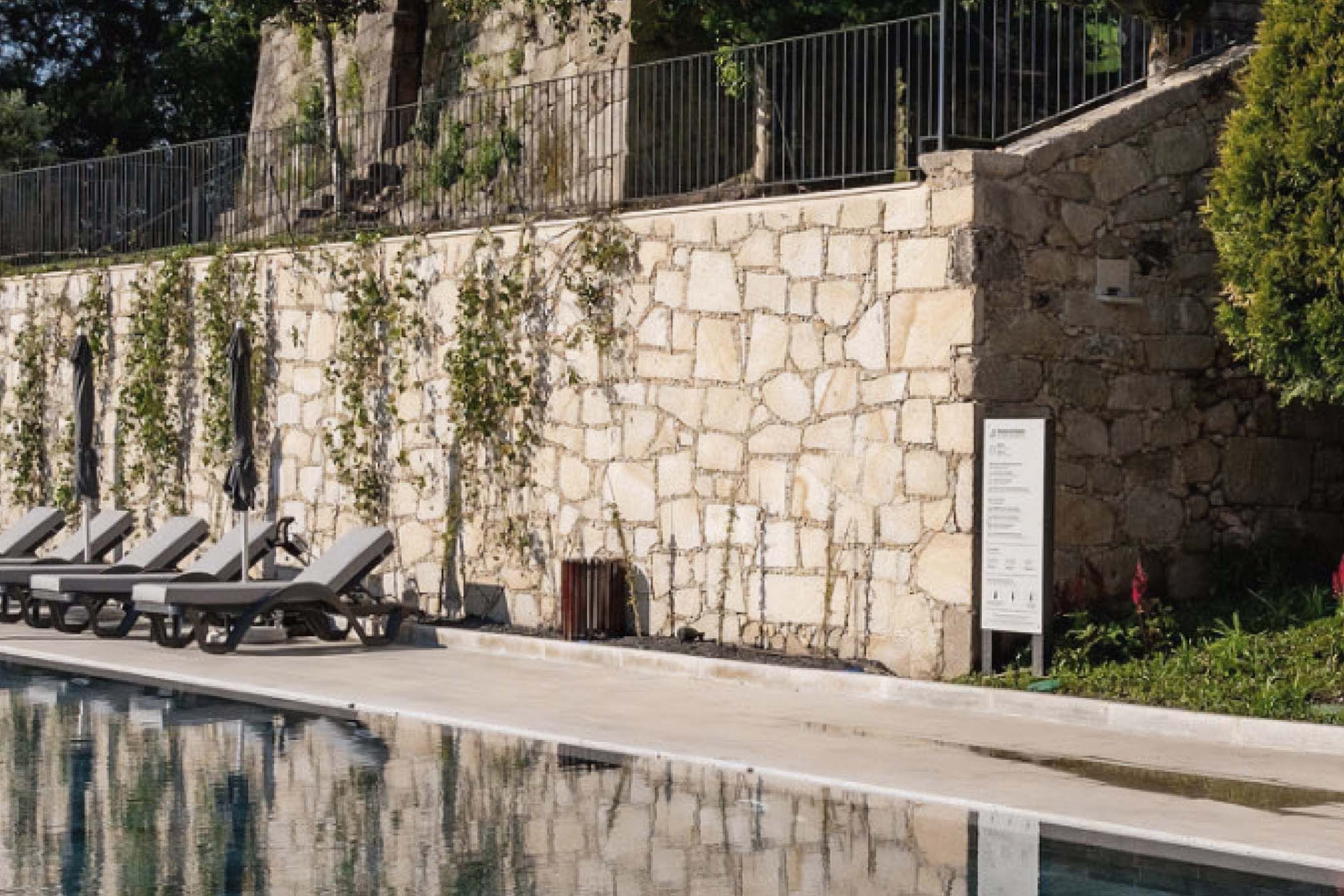 Zona de piscina exterior de hotel con tótem informativo en HPL+ y plástico reciclado.