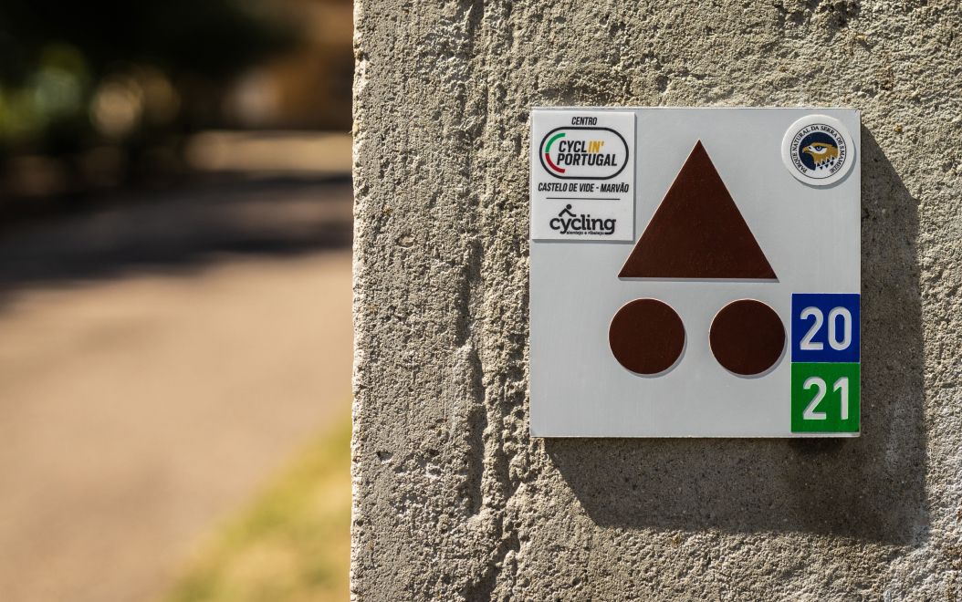 Detalle de placa base Centros Cyclin' Portugal con adhesivos de recorrido y de homologación, instalada en pared.