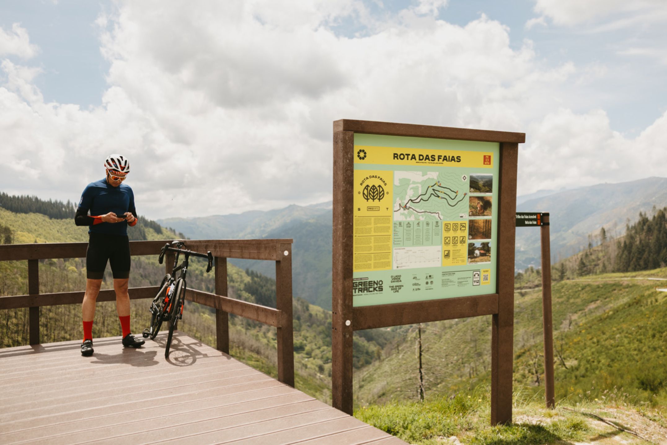 Fotografía en la Serra da Estrela con un ciclista en pausa sobre un mirador fabricado en plástico reciclado, modelo floema, y con panel informativo ICNF para áreas protegidas, con panel interior en HPL Print con mapa de ruta.