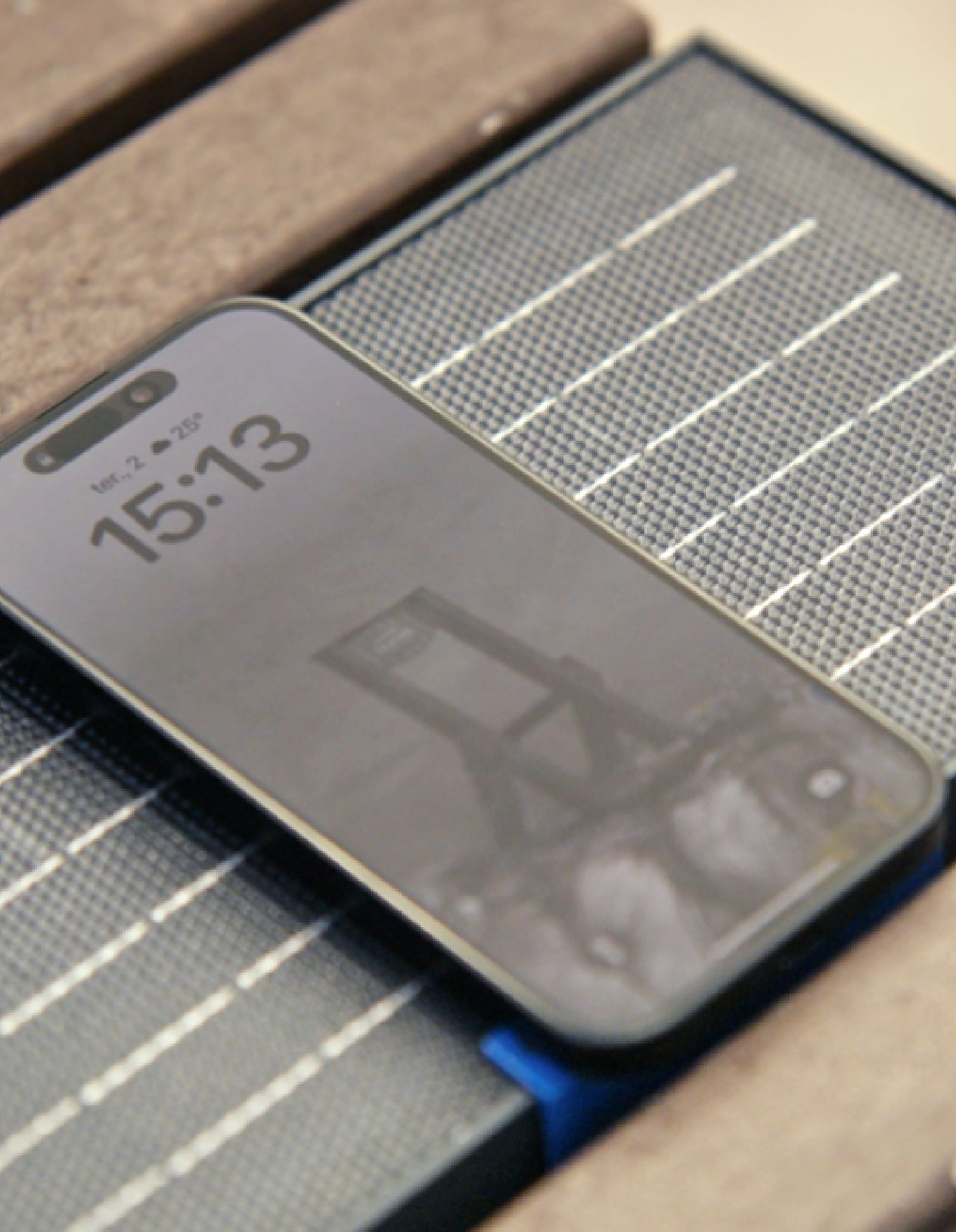 Primer plano de un teléfono móvil cargándose en un banco inteligente, que muestra perfiles de plástico reciclado y un módulo de carga solar.