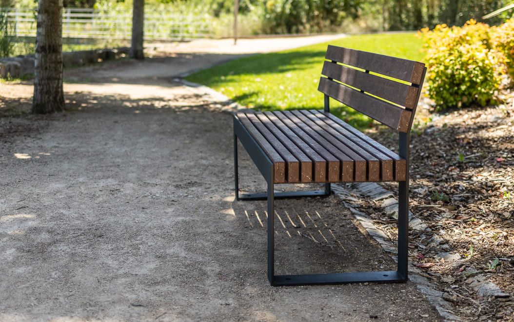 Banco urbano duradero instalado en un parque urbano con respaldo de la línea Frame de Floema, fabricado con plástico 100% reciclado y reciclable.