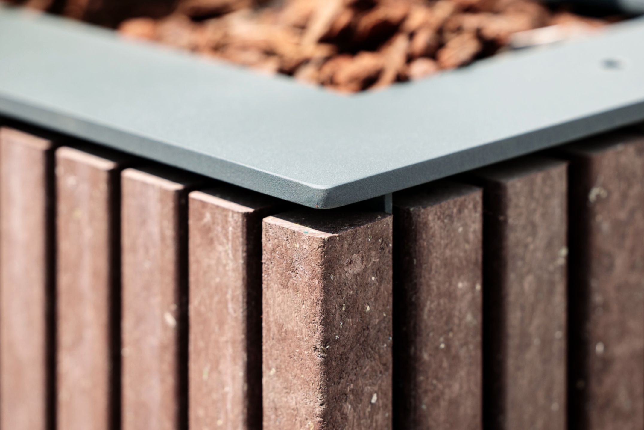 Detalle de jardinera Floema de la línea Frame, con estructura de acero metalizado y pintado y plástico reciclado marrón.