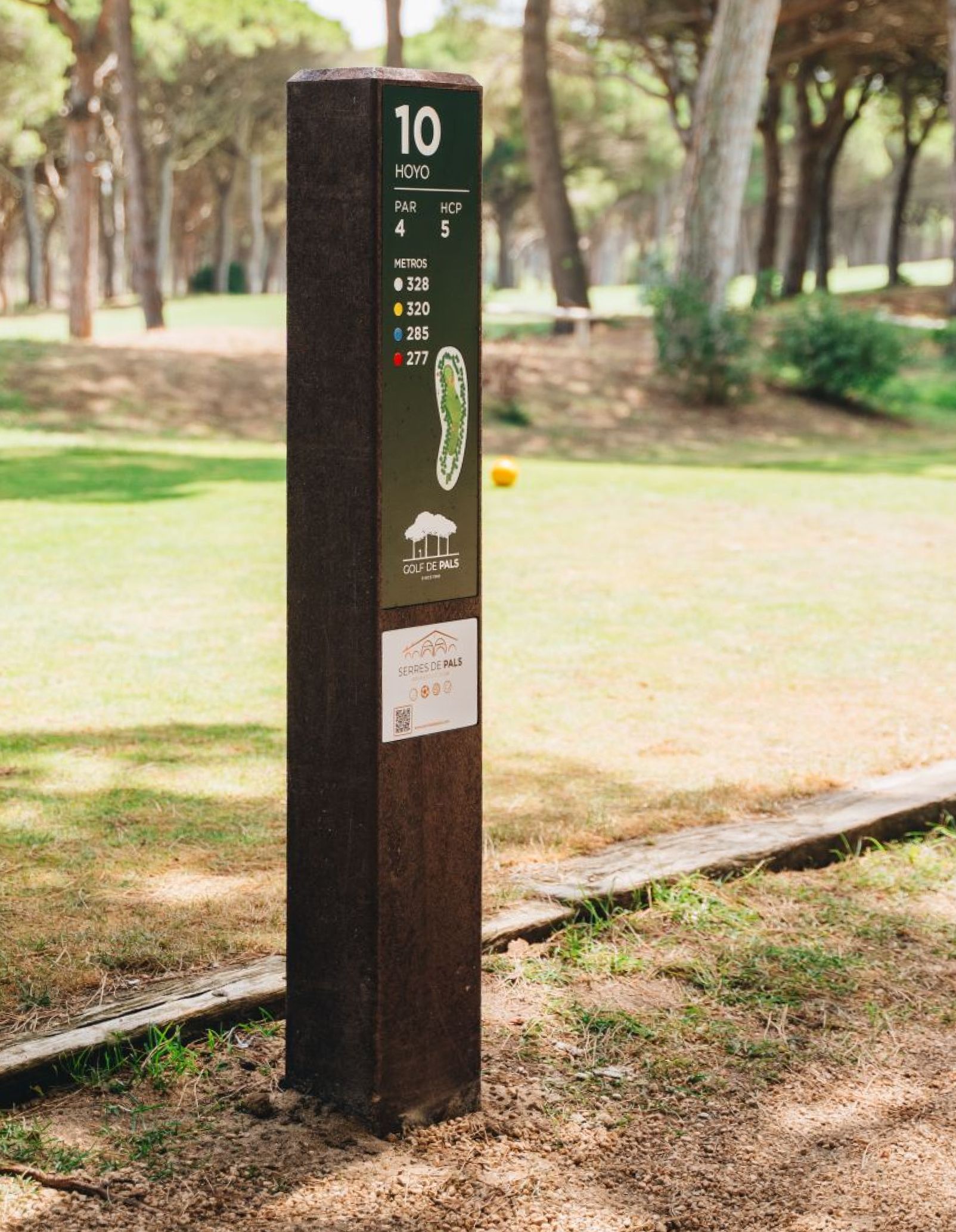 Tee totem Royal en zona de salida en campo de golf. Con estructura en plástico reciclado marrón y HPL+ y con una pequeña zona de publicidad.