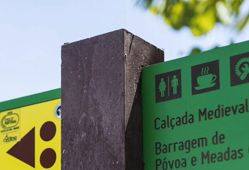 Detalle de placa direccional Centros Cyclin' Portugal en HPL+ empotrada en poste de plástico reciclado marrón.