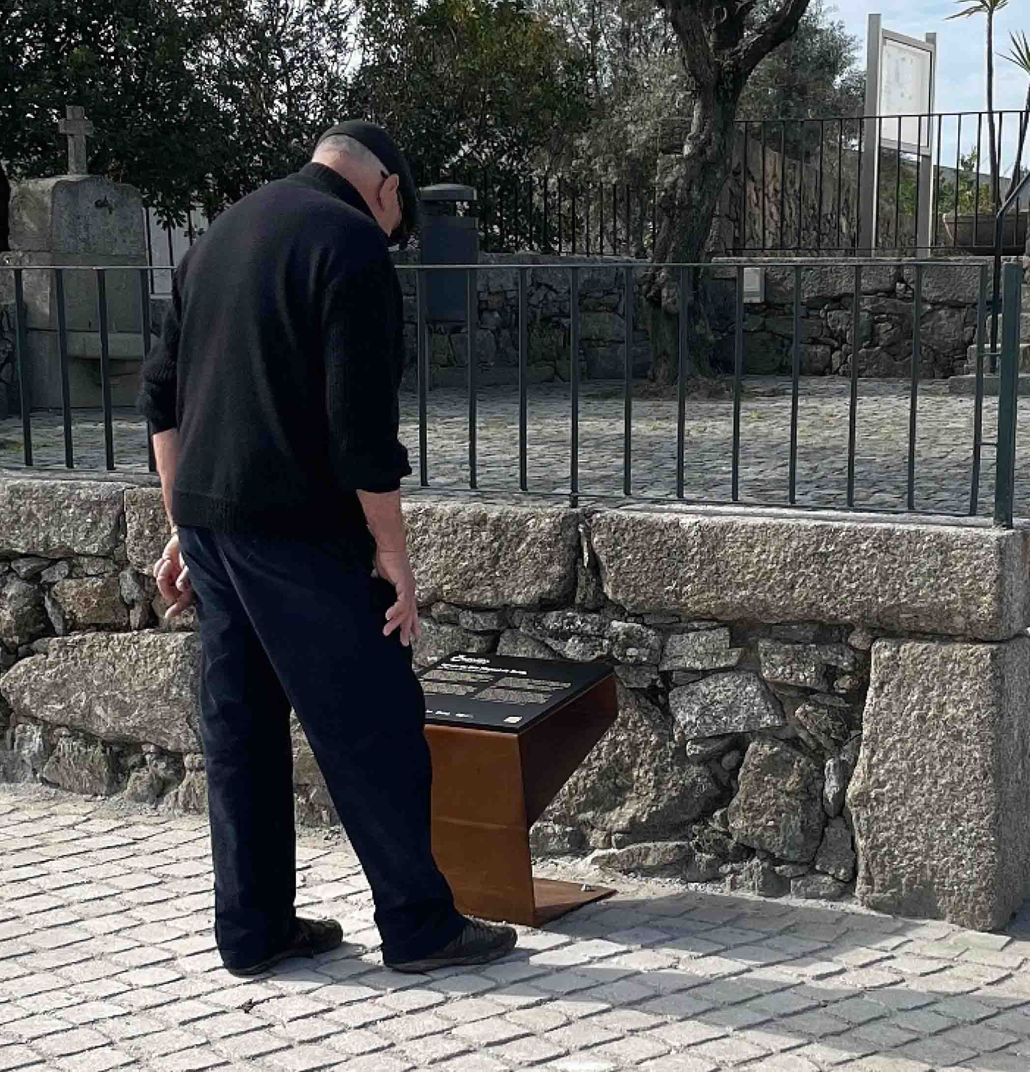 Hombre leyendo el contenido de una mesa interpretativa personalizada de un monumento, integrada en una ruta urbana, producida en acero corten y HPL+.