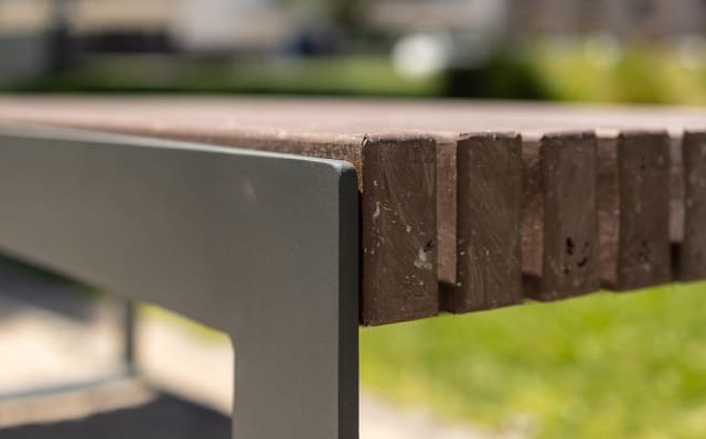 Detalle de un banco urbano moderno sin respaldo, fabricado con plástico reciclado.