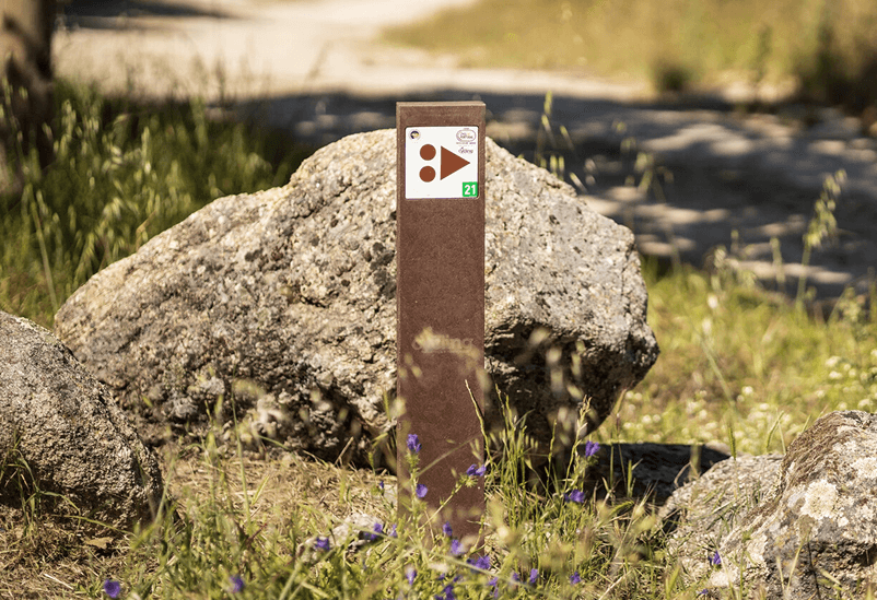 Detalle de baliza de plástico reciclado Centros Cyclin' Portugal personalizada con placa direccional de base empotrada, en espacio natural.