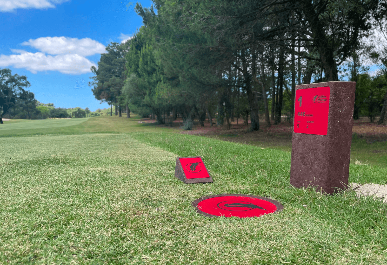 Log marker, disc marker y tee marker en la zona de salida del campo de golf. Todos fabricados con estructura de plástico reciclado marrón y con información grabada con láser y CNC en HPL rojo.