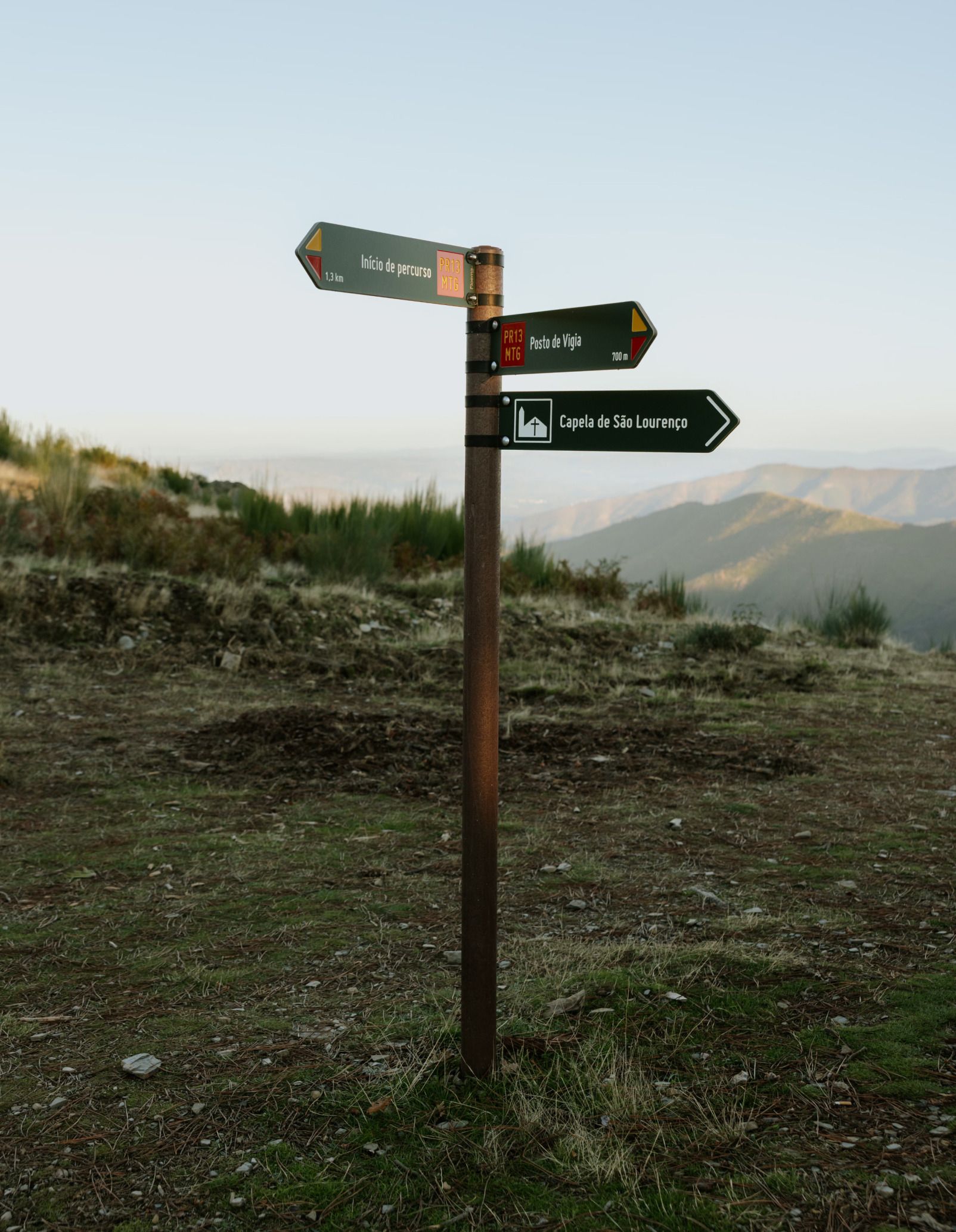 Placas direccionales para recorridos peatonales en HPL+, modelo Floema, con sistema de fijación mediante abrazaderas y poste de plástico reciclado marrón, en área natural protegida.